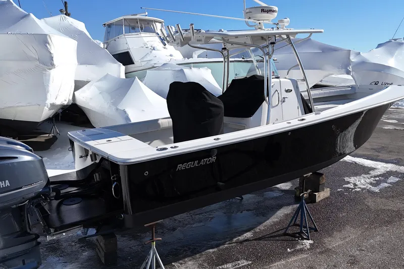 Slide: The Image of 2011 Regulator 28 Forward Seating boat in storage, surrounded by covered vessels. - 2