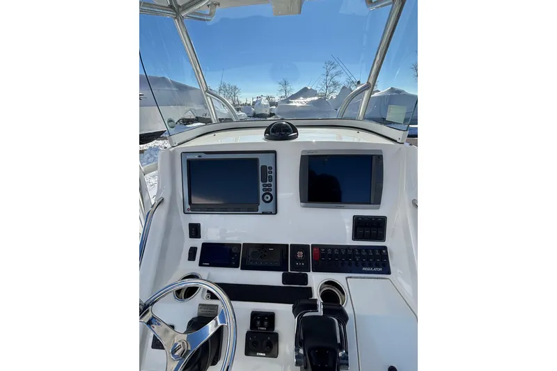Slide: The Image of 2011 Regulator 28 Forward Seating boat dashboard with dual screens and steering wheel. - 21