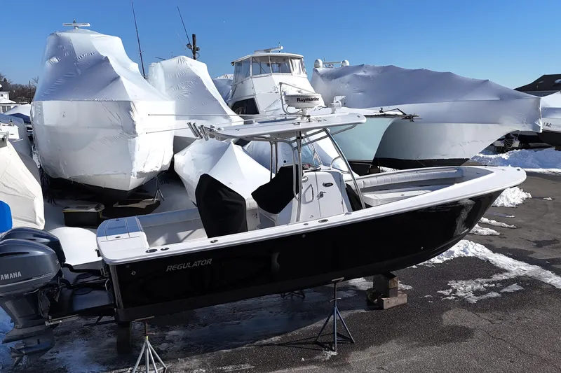 Slide: The Image of 2011 Regulator 28 Forward Seating boat in storage, surrounded by snow-covered vessels. - 4