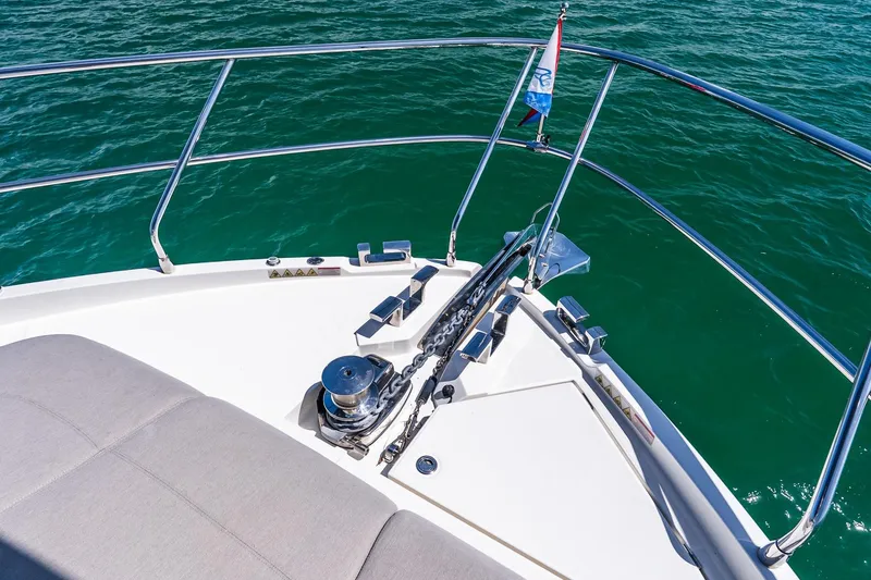 Slide: The Image of Bow of 2022 Absolute 64 Navetta yacht with anchor and railing over turquoise water. - 33