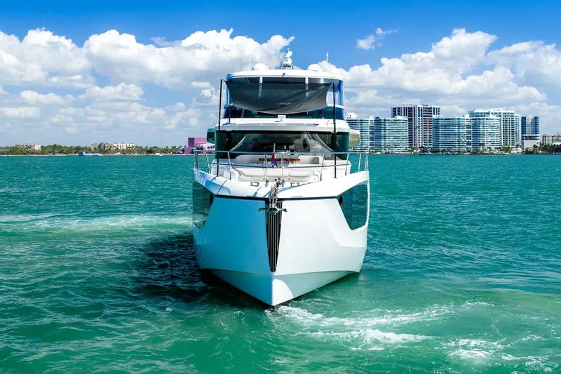 Slide: The Image of Front view of 2022 Absolute 64 Navetta yacht on turquoise water, city skyline in background. - 17