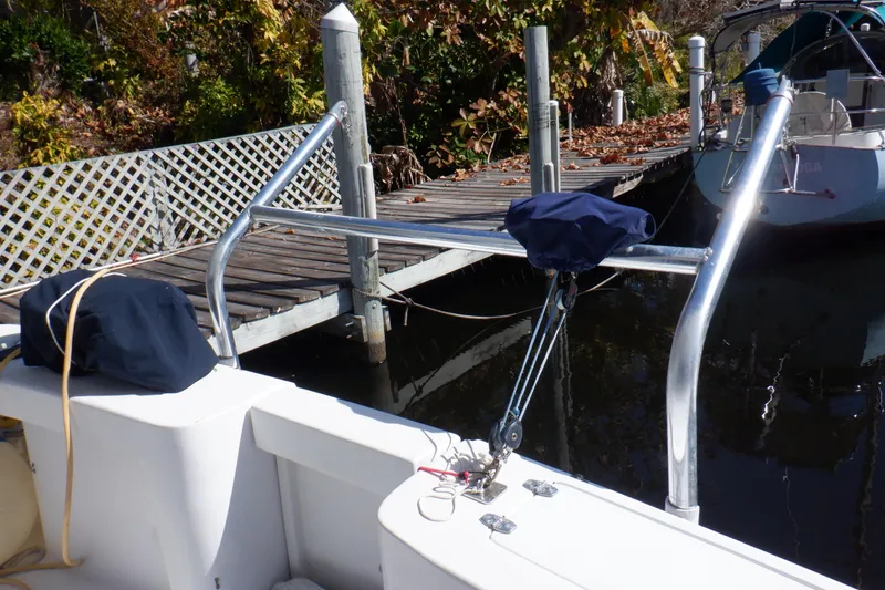 Slide: The Image of 1999 Mainship 350 Trawler docked, featuring deck equipment and nearby wooden pier. - 10