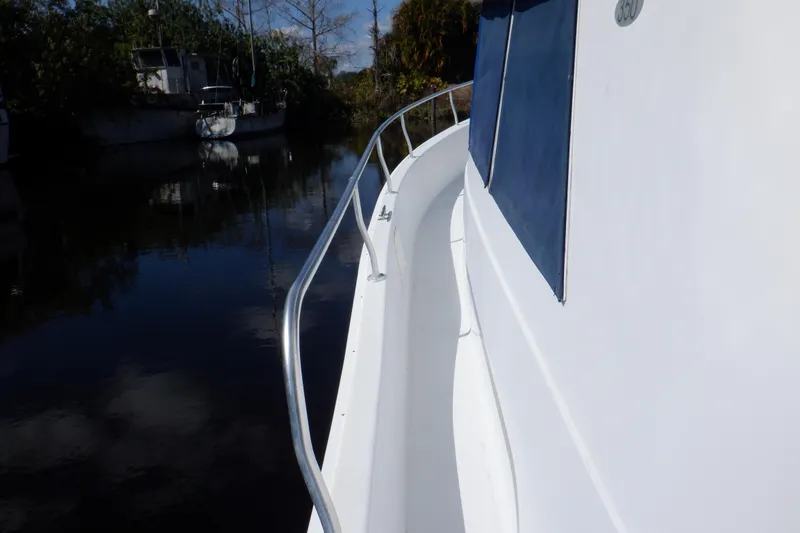 Slide: The Image of 1999 Mainship 350 Trawler side deck view with railing, docked near other boats. - 11