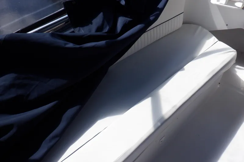 Slide: The Image of White seating area on a 1999 Mainship 350 Trawler, partially covered by a dark fabric. - 23