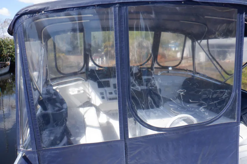 Slide: The Image of 1999 Mainship 350 Trawler cockpit with clear enclosure and steering wheel visible. - 27