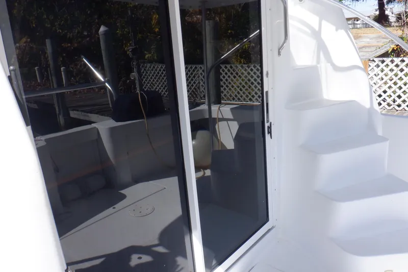 Slide: The Image of 1999 Mainship 350 Trawler with white exterior, glass door, and steps leading to upper deck. - 29