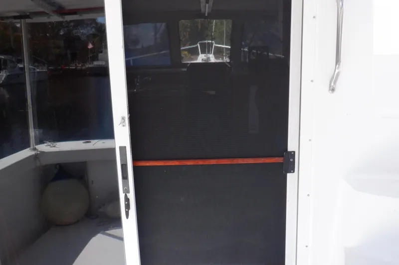 Slide: The Image of 1999 Mainship 350 Trawler screen door with handle, docked in marina. - 30