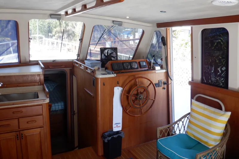 Slide: The Image of 1999 Mainship 350 Trawler interior with wooden helm, seating, and cabin view. - 33