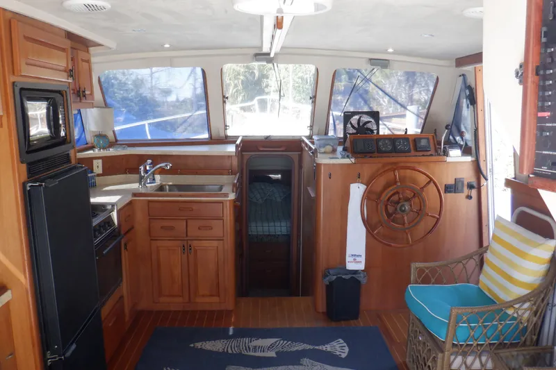 Slide: The Image of Interior of 1999 Mainship 350 Trawler with kitchen and helm, featuring wooden cabinetry. - 34