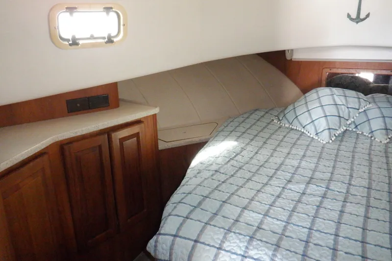 Slide: The Image of 1999 Mainship 350 Trawler cabin interior with bed, pillows, and wooden cabinetry. - 42