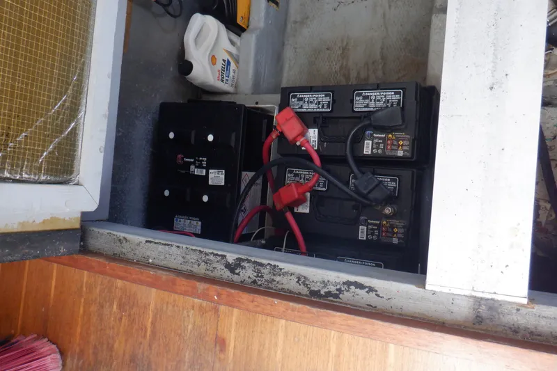 Slide: The Image of Battery compartment of a 1999 Mainship 350 Trawler with connected cables and oil container. - 49