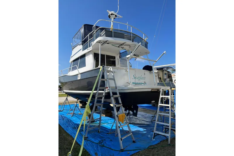 Slide: The Image of 1999 Mainship 350 Trawler on dry dock, undergoing maintenance with ladders and tarp. - 59