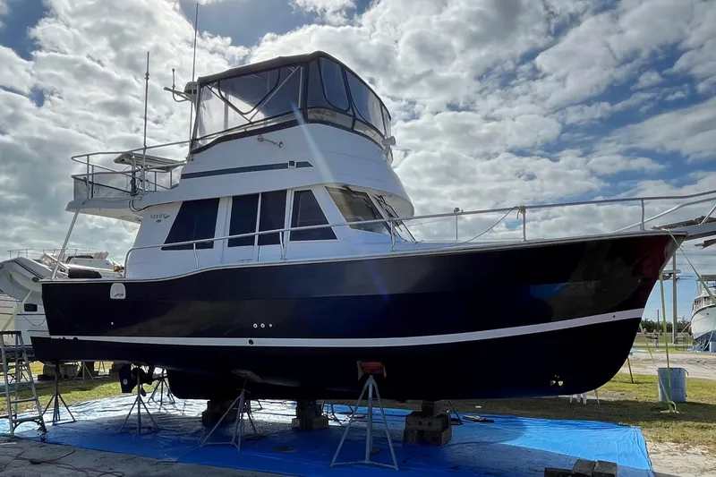 Slide: The Image of 1999 Mainship 350 Trawler on stands, under cloudy sky, side view. - 66