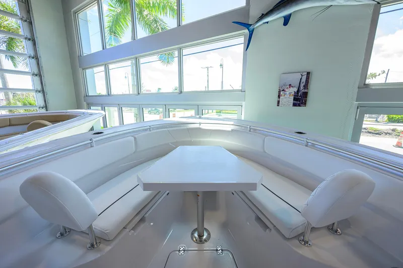 Slide: The Image of 2026 Sportsman Open 252 Center Console boat interior with seating and table, in a bright showroom. - 12