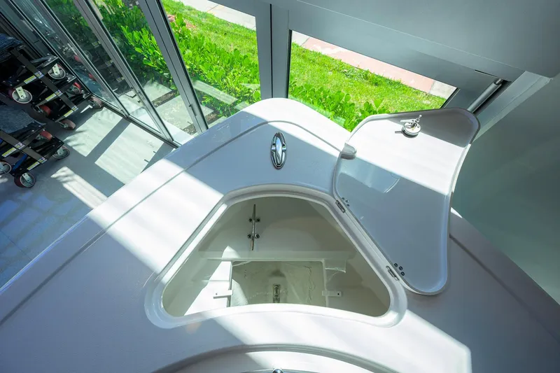 Slide: The Image of 2026 Sportsman Open 252 Center Console boat storage compartment, open lid, sunlight streaming in. - 15