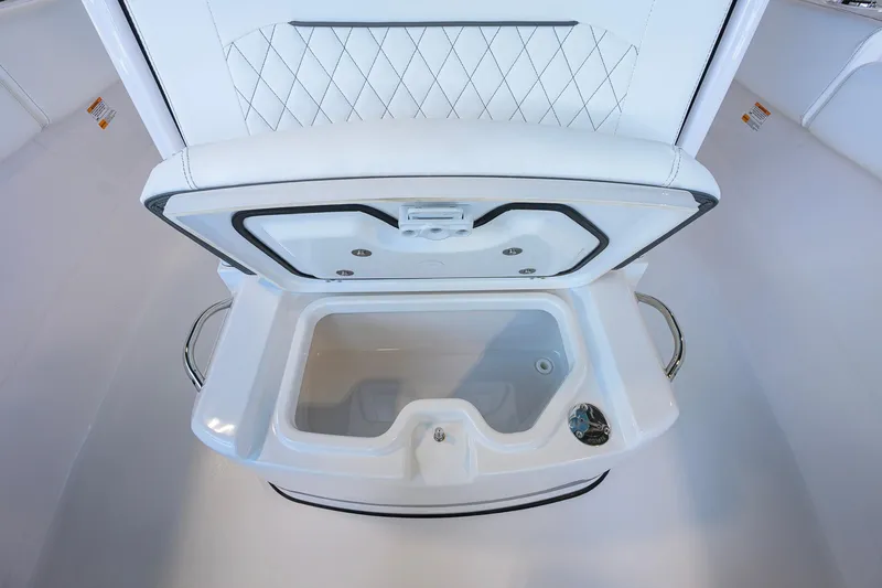 Slide: The Image of 2026 Sportsman Open 252 Center Console boat's open storage compartment with white cushioned lid. - 18
