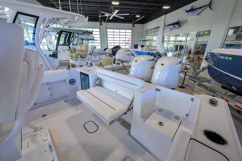 Slide: The Image of 2026 Sportsman Open 252 Center Console boat interior in showroom with seating and engines. - 30