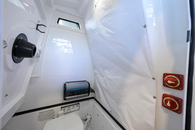 Slide: The Image of 2026 Sportsman Open 252 Center Console interior cabin with marine toilet and controls. - 43