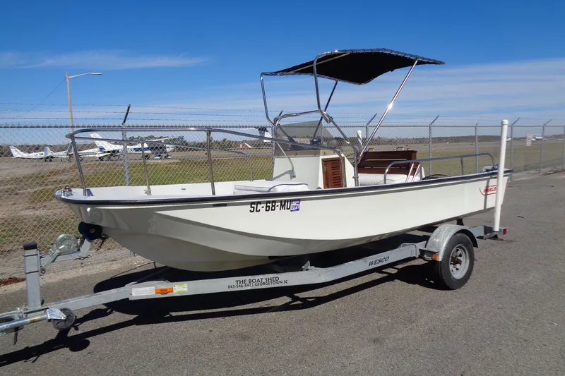 The Image of 1987 Boston Whaler Montauk 17' CC boat on trailer, parked near airfield. - 1