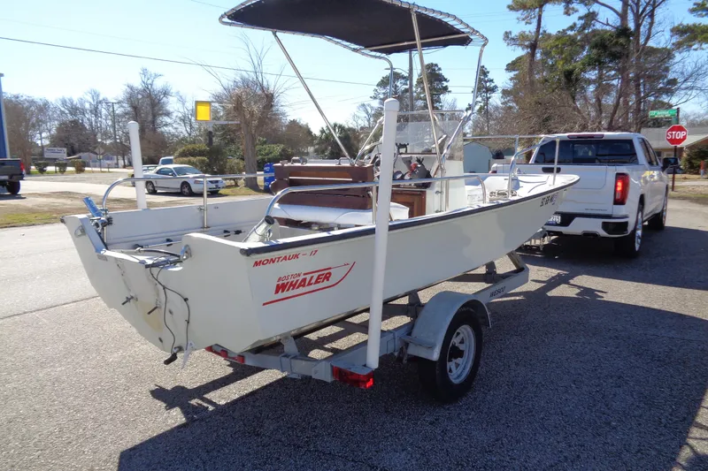 Slide: The Image of 1987 Boston Whaler Montauk 17' CC boat on trailer, parked near a white truck. - 4