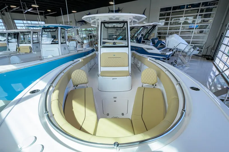 Slide: The Image of 2026 Sportsman Open 232 Center Console boat interior with beige seating in showroom. - 16