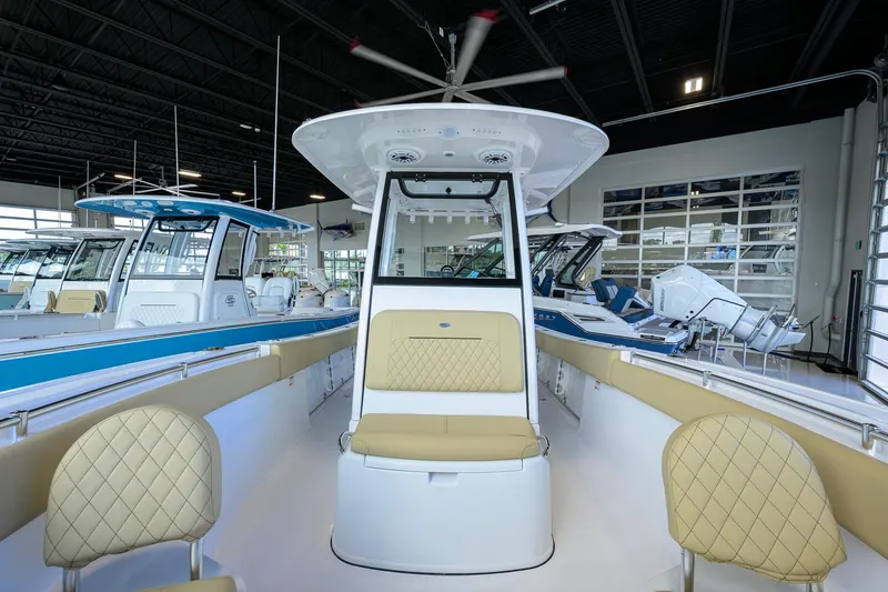 Slide: The Image of 2026 Sportsman Open 232 Center Console boat interior with beige seating in showroom. - 17