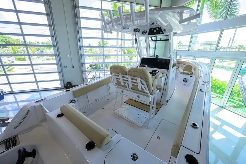 Slide: The Image of 2026 Sportsman Open 232 Center Console boat interior with beige seating in a sunlit showroom. - 29