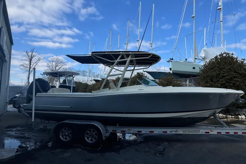 Slide: The Image of 2017 Chris-Craft Calypso 26 boat on trailer, docked with sailboats in background. - 5