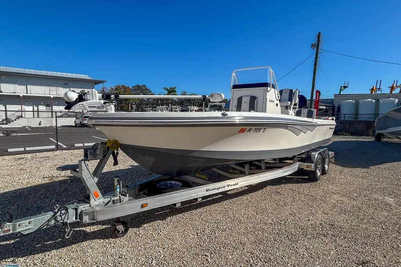 Slide: The Image of 2022 Ranger 2360 Bay boat on trailer, parked outdoors under clear blue sky. - 5