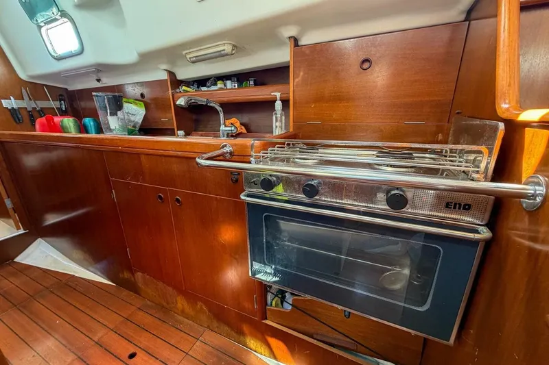 Slide: The Image of 1998 Beneteau Oceanis 36 CC yacht kitchen with stove, sink, and wooden cabinetry. - 28