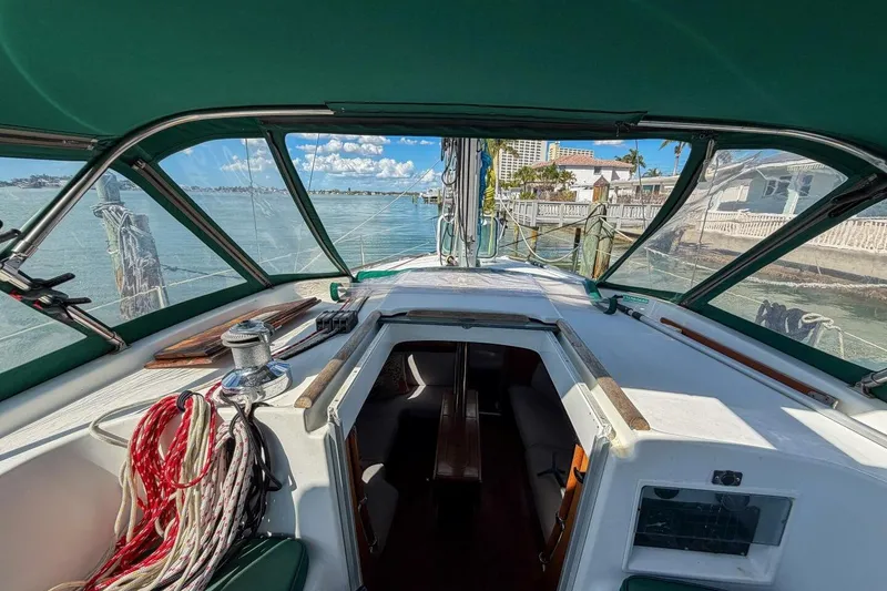 Slide: The Image of 1998 Beneteau Oceanis 36 CC sailboat cockpit with green canopy, docked by waterfront homes. - 51