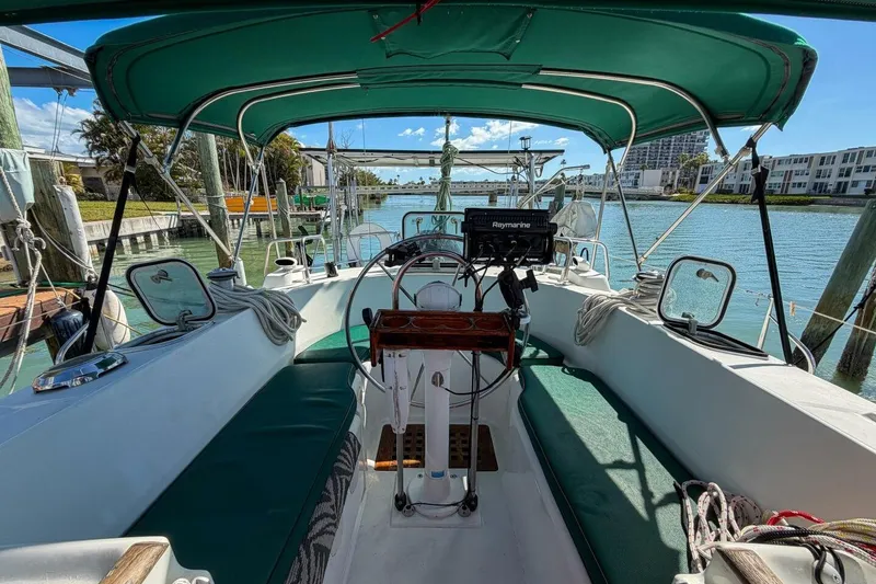 Slide: The Image of 1998 Beneteau Oceanis 36 CC sailboat cockpit with green canopy, docked by waterfront homes. - 58
