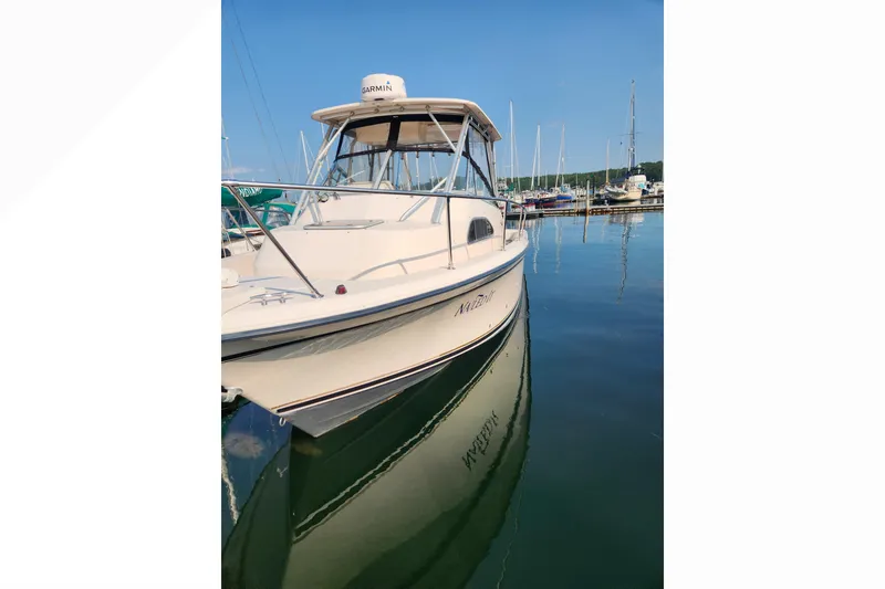 Slide: The Image of 1999 Grady-White Marlin 300 boat docked in a marina, reflecting on calm water. - 6