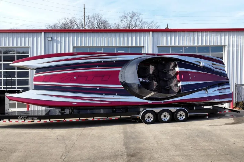 The Image of 2018 MTI 43 R/P powerboat on trailer, vibrant red and black design, parked outside a building. - 0