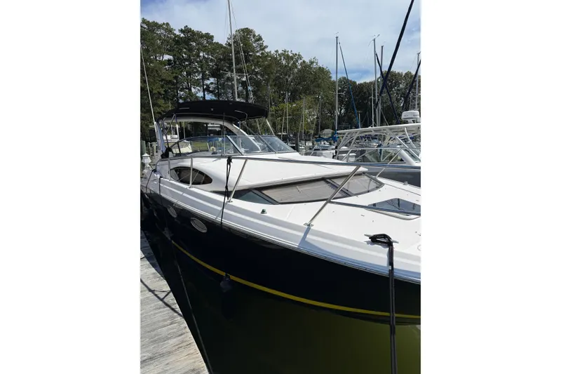 The Image of 2010 Regal 3360 Window Express boat docked at marina, surrounded by trees and other boats. - 0