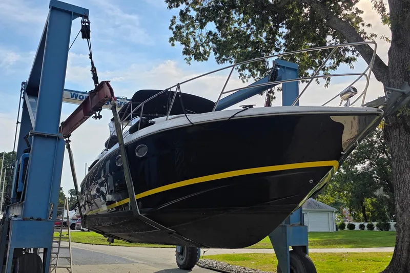 Slide: The Image of 2010 Regal 3360 Window Express boat on lift, black hull, yellow stripe, outdoor setting. - 3
