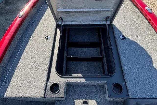 Slide: The Image of 2025 Tracker Pro Team 190 boat storage compartment with open lid, featuring gray carpeted interior. - 11