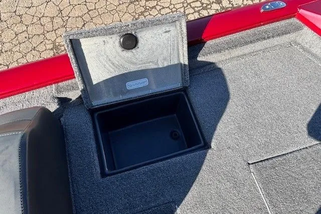 Slide: The Image of Open storage compartment in 2025 Tracker Pro Team 190 boat, featuring gray carpet and red trim. - 21