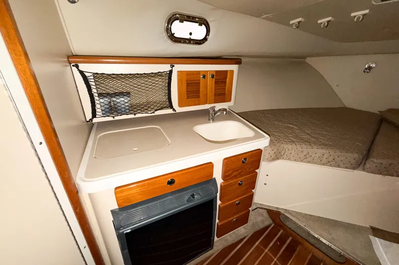 Slide: The Image of 2007 Pursuit OS 335 Offshore cabin interior with kitchenette and bed. - 12