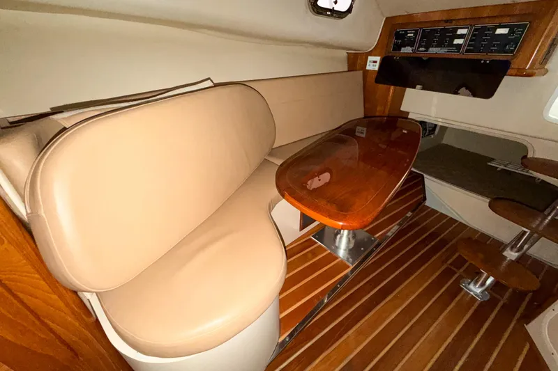 Slide: The Image of 2007 Pursuit OS 335 Offshore cabin interior with beige seating and wooden table. - 14