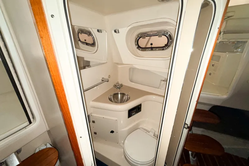 Slide: The Image of 2007 Pursuit OS 335 Offshore boat bathroom with sink, toilet, and porthole window. - 17
