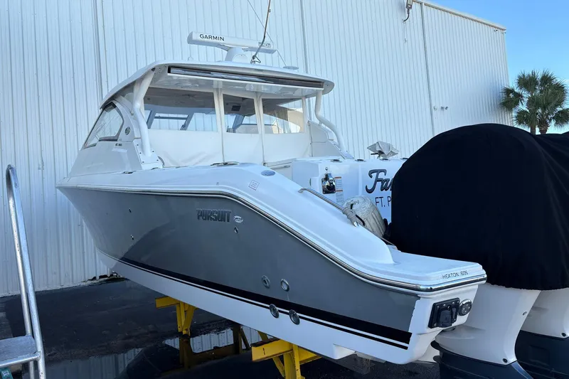 Slide: The Image of 2020 Pursuit DC 365 Dual Console boat docked near a white building. - 20