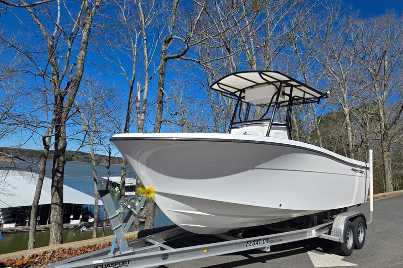Slide: The Image of 2024 Aquasport 2100 Center Console on trailer, near lake and trees. - 18