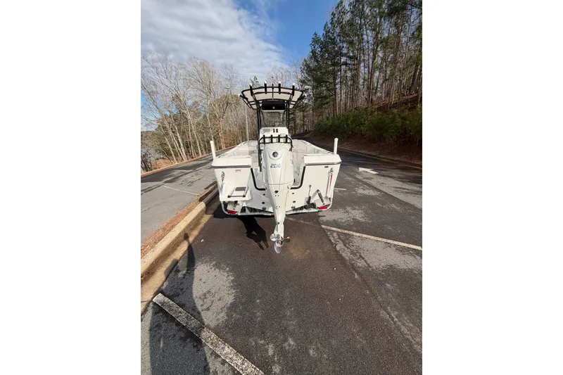 Slide: The Image of 2024 Aquasport 2100 Center Console boat on trailer, parked on a wooded road. - 4
