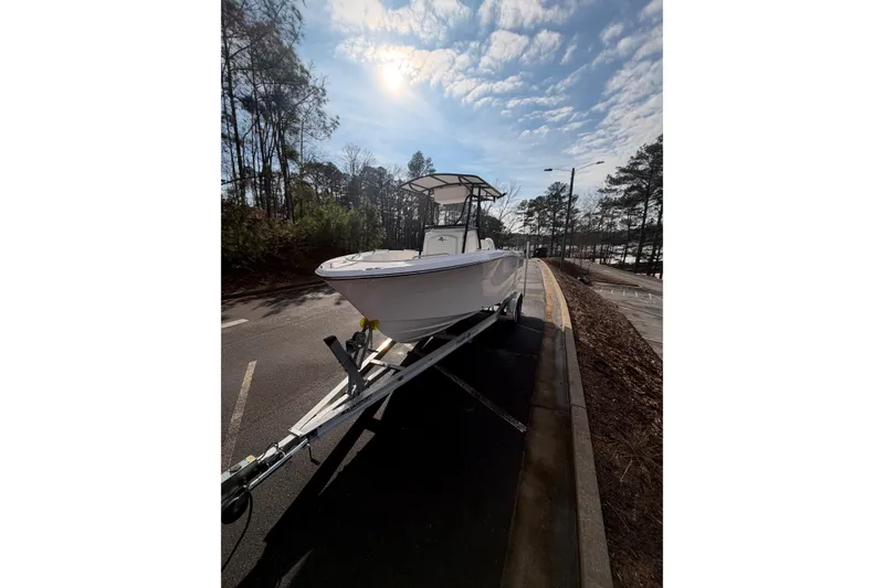 Slide: The Image of 2024 Aquasport 2100 Center Console boat on trailer under a sunny sky. - 8