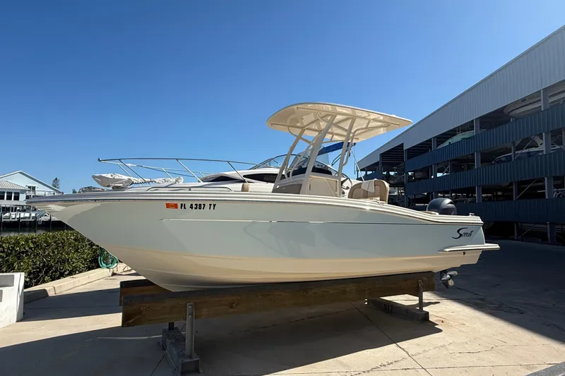 The Image of 2021 Scout 215 XSF boat on display at a marina under clear blue sky. - 1