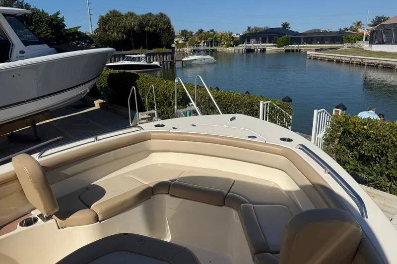 Slide: The Image of 2021 Scout 215 XSF boat docked by a scenic waterfront with lush greenery. - 14