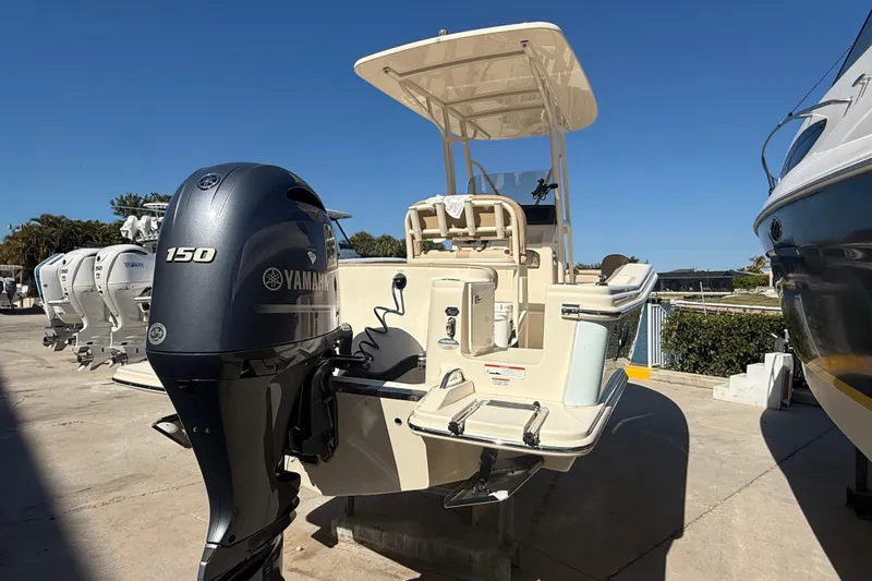 Slide: The Image of 2021 Scout 215 XSF boat with Yamaha 150 outboard motor, docked under clear blue sky. - 6
