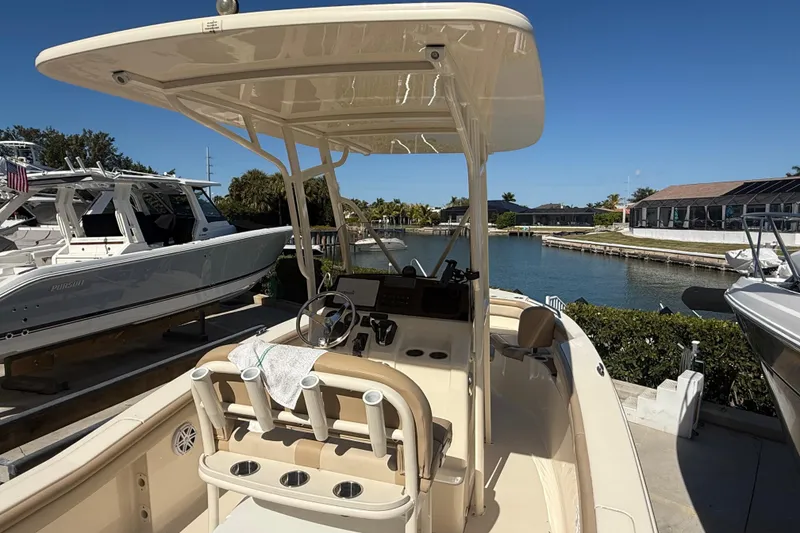 Slide: The Image of 2021 Scout 215 XSF boat docked near waterfront homes under clear blue sky. - 9