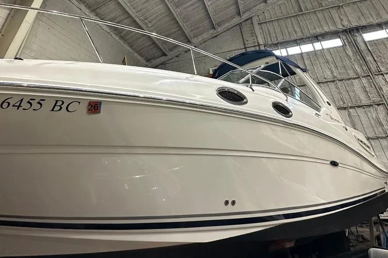 The Image of 2007 Sea Ray Sundancer 260 boat in a warehouse, showcasing sleek design and white exterior. - 0
